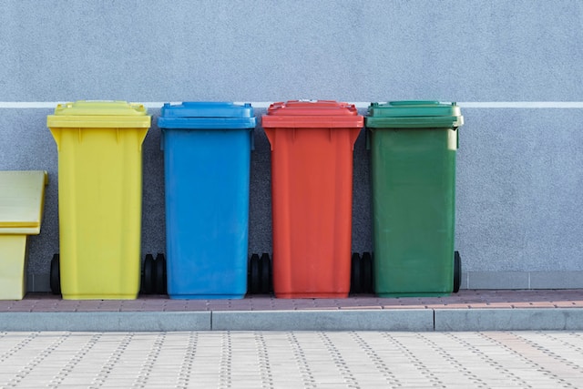 Cubos de basura de una comunidad de vecinos colocados en fila
